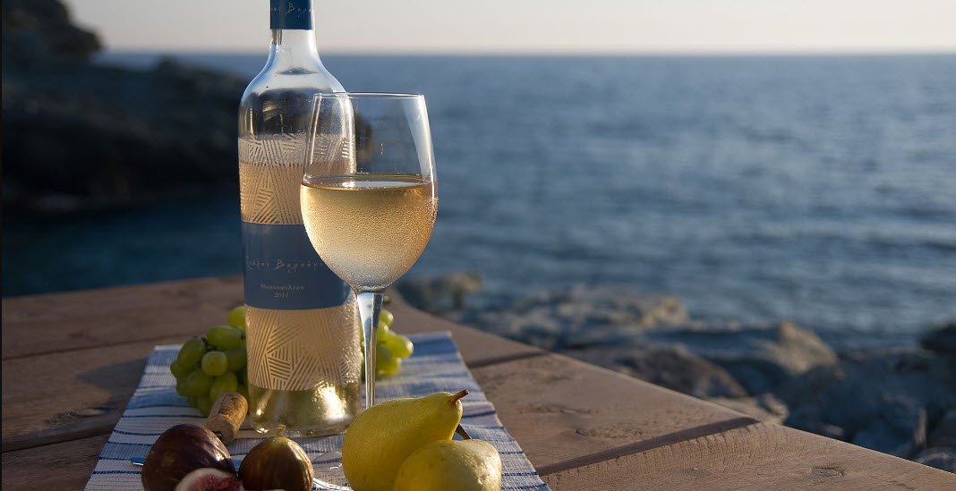На фото хорошее греческое вино с фруктами у берега моря