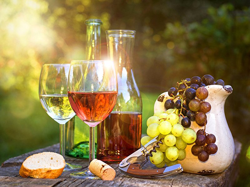 Фотография: лучи солнца падают на кувшин с виноградными ягодами, графин с вином и бокалы