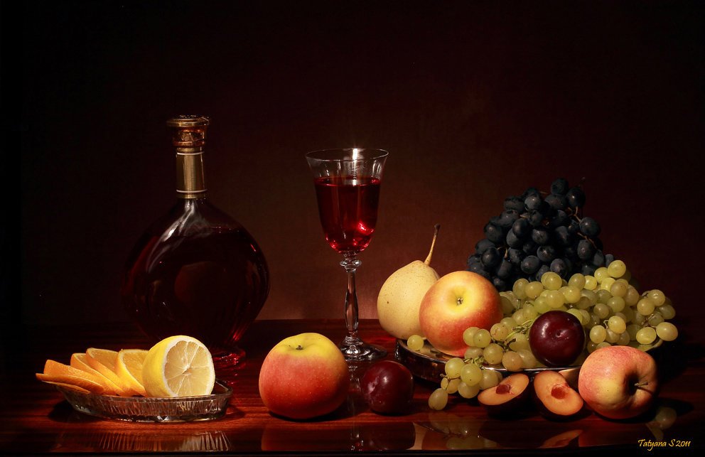 Натюрморт: бутылка крепленого коллекционного вина, наполненный бокал с вином, ягоды, цитрусы и фрукты