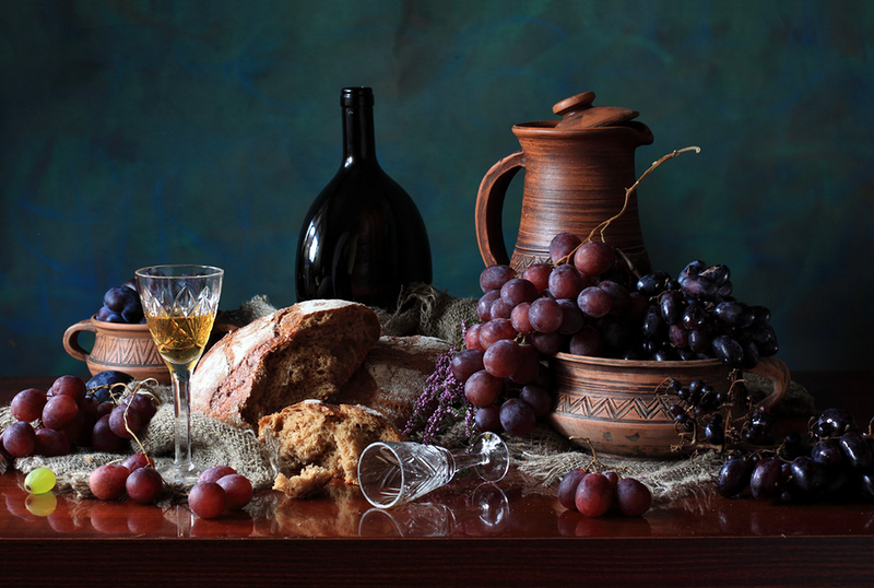 Винтажная картинка: на столе стоит эксклюзивная бутылка вина, глиняный графин, бокалы, лежит надломленный хлеб и виноград