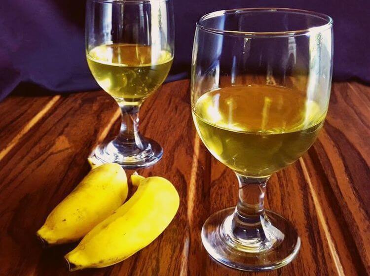 На фотографии банановое вино в бокалах на столе с бананами