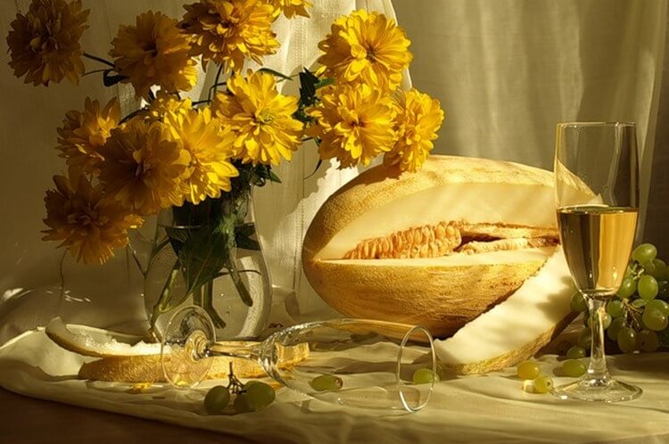 Красивая картинка: бокал вина, разрезанная дыня, букет цветов в вазе