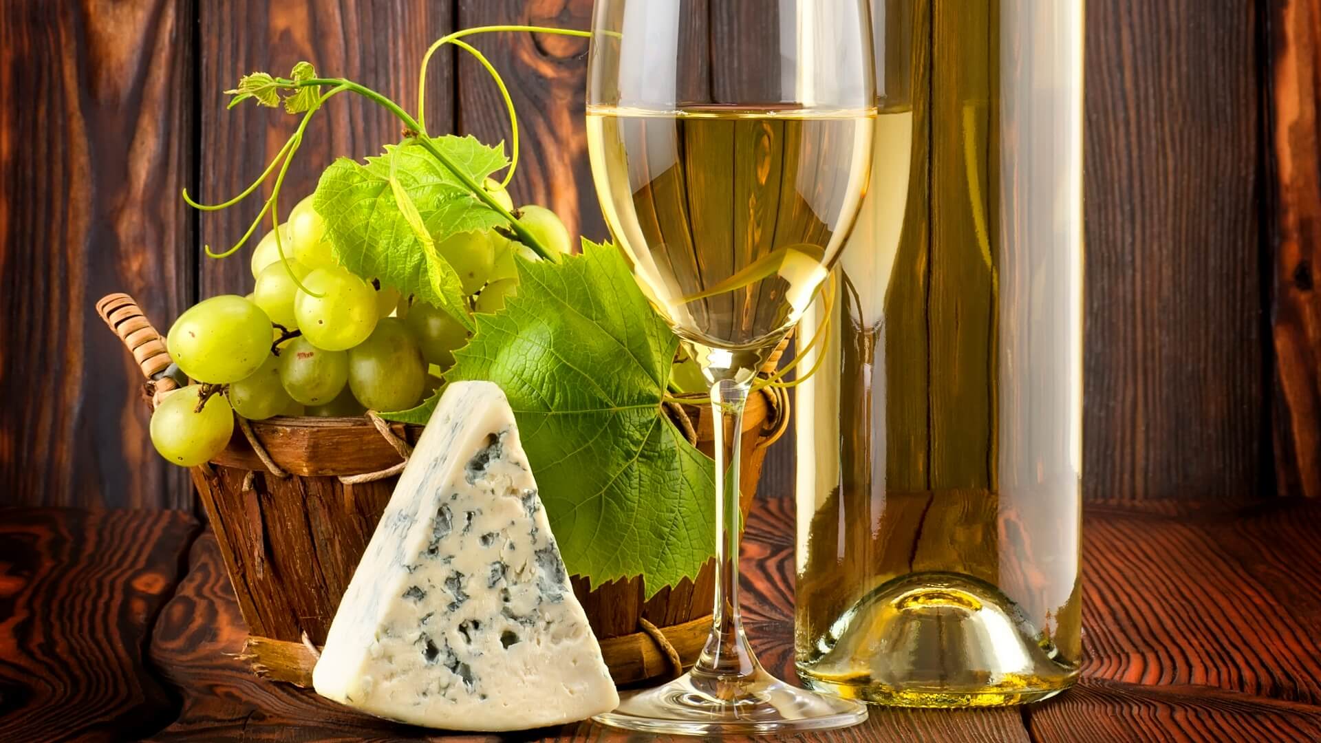 Натюрморт: бокал белого вина, корзина с ягодами и кусочек сыра