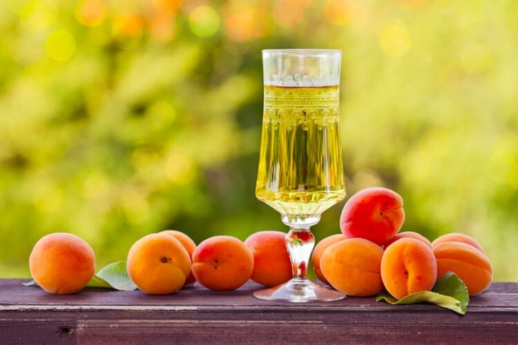 Абрикосовое вино в бокале на столе с самими фруктами