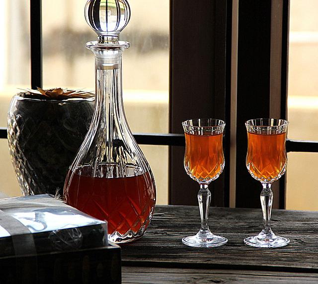 На фотографии изображено крыжовниковое ягодное вино в графине с бокалами