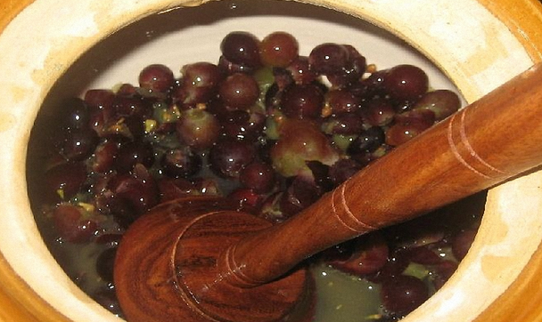 На фотографии показан процесс размельчения ягод крыжовника в горшке
