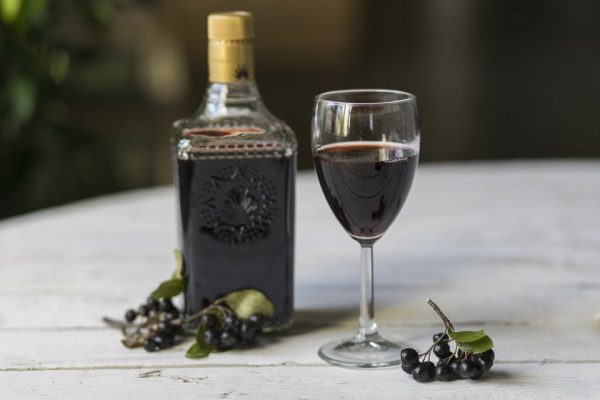 На фотографии вино из черной смородины в бутылке и бокале